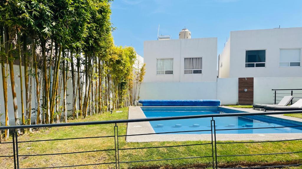 约里奇拉Acogedora y amplia casa, alberca climatizada previa reserva的一座树木繁茂的建筑前的游泳池