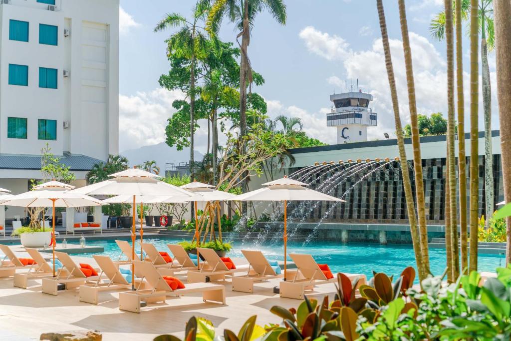 珍南海滩Wings by Croske Resort Langkawi的一座带躺椅和遮阳伞的游泳池位于大楼旁