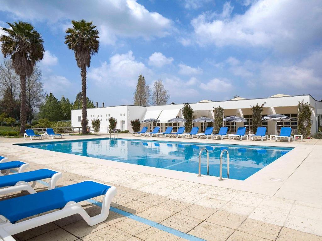 塞图巴尔塞图巴尔诺富特酒店的一个带蓝色椅子和棕榈树的大型游泳池