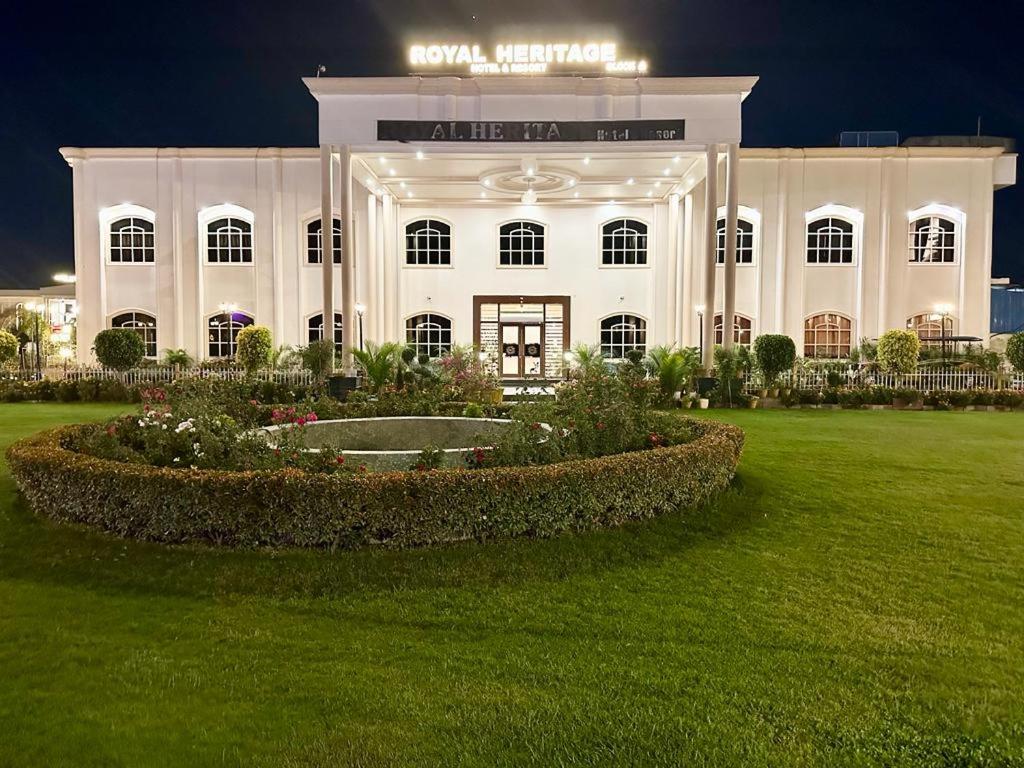AyodhyaRoyal Heritage Hotel & Resort的一座白色的大建筑,前面有一个花园