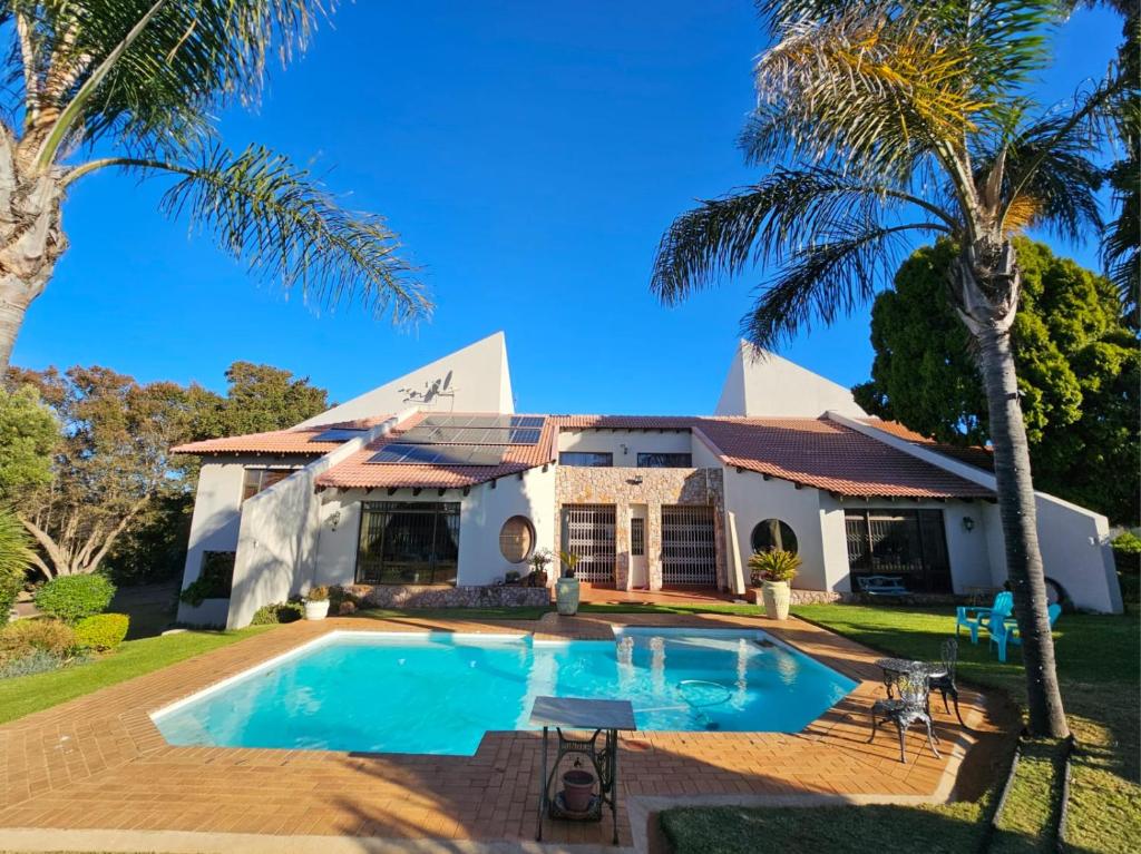 海德堡Epicure Home Guesthouse的一座带游泳池和棕榈树的房子