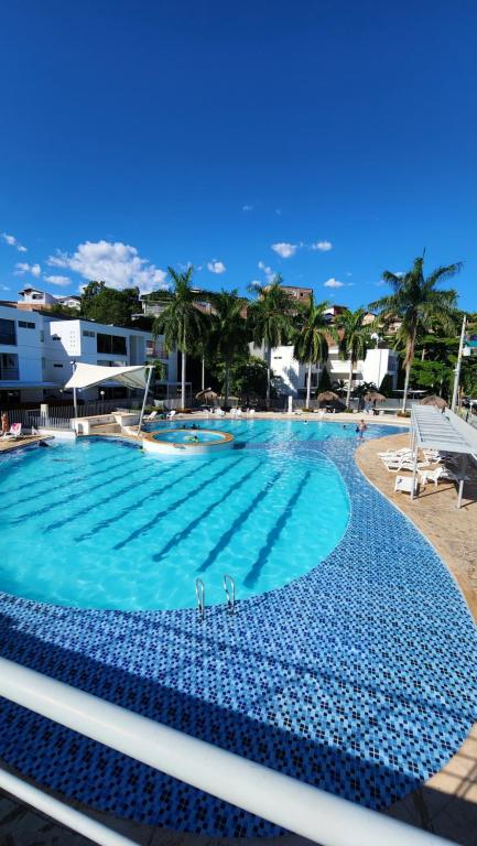 圣菲德安蒂奥基亚Apartasol Club Ciudadela Santa Fe - Santa Fe de Antioquia的一座拥有蓝色海水和棕榈树的大型游泳池