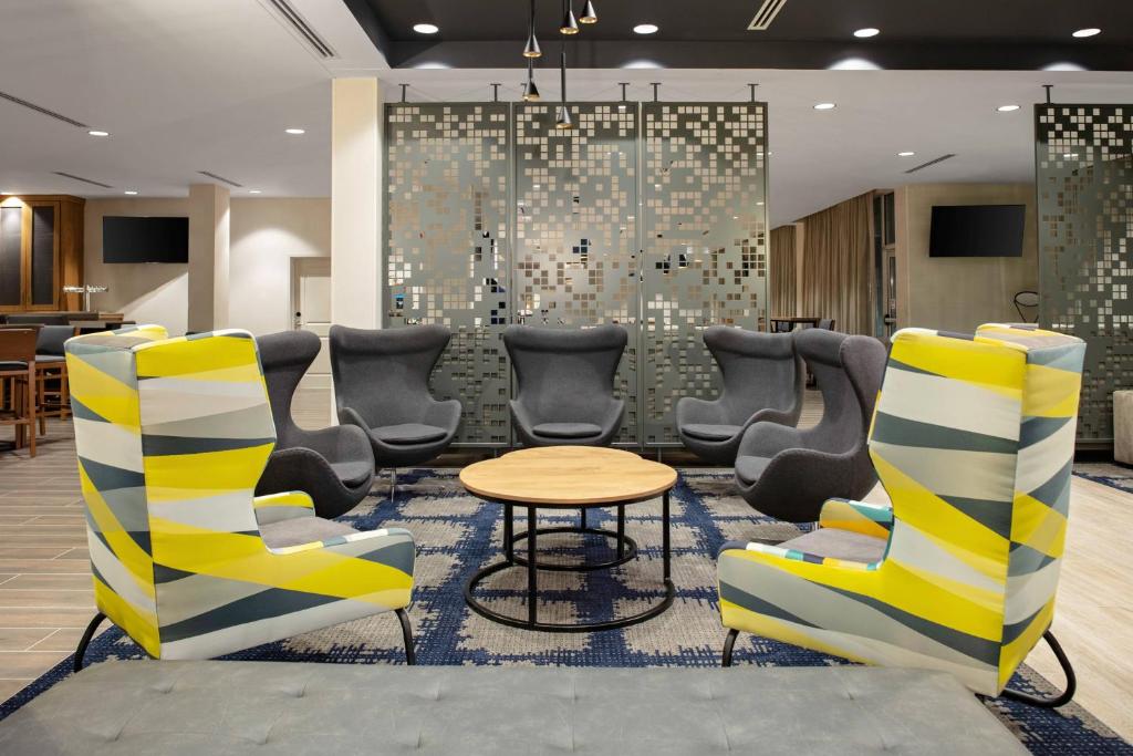 奥兰多TownePlace Suites by Marriott Orlando Airport的一间设有椅子、桌子和墙壁的等候室