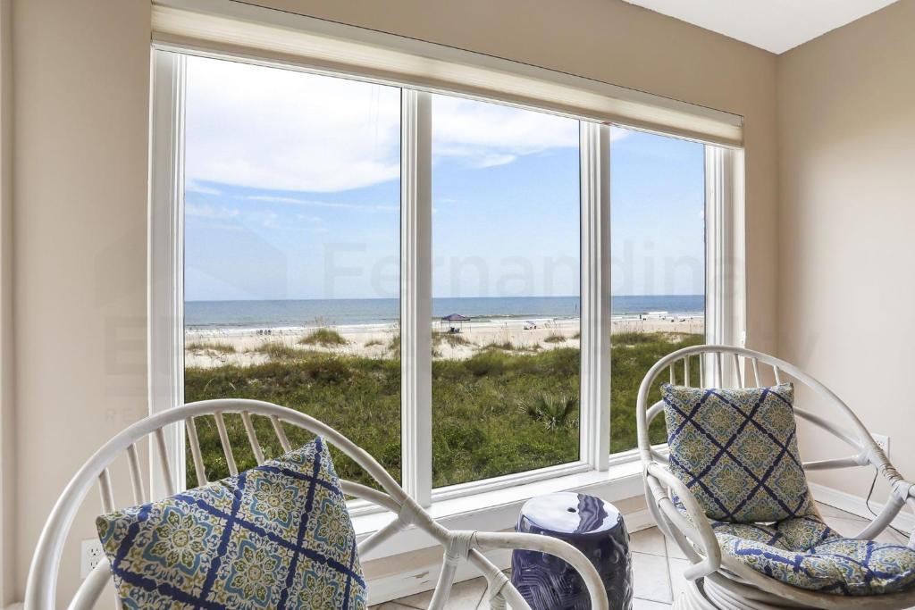 费南迪纳比奇Oceans Of Amelia - 102的客房设有两把椅子和一扇俯瞰海滩的窗户。