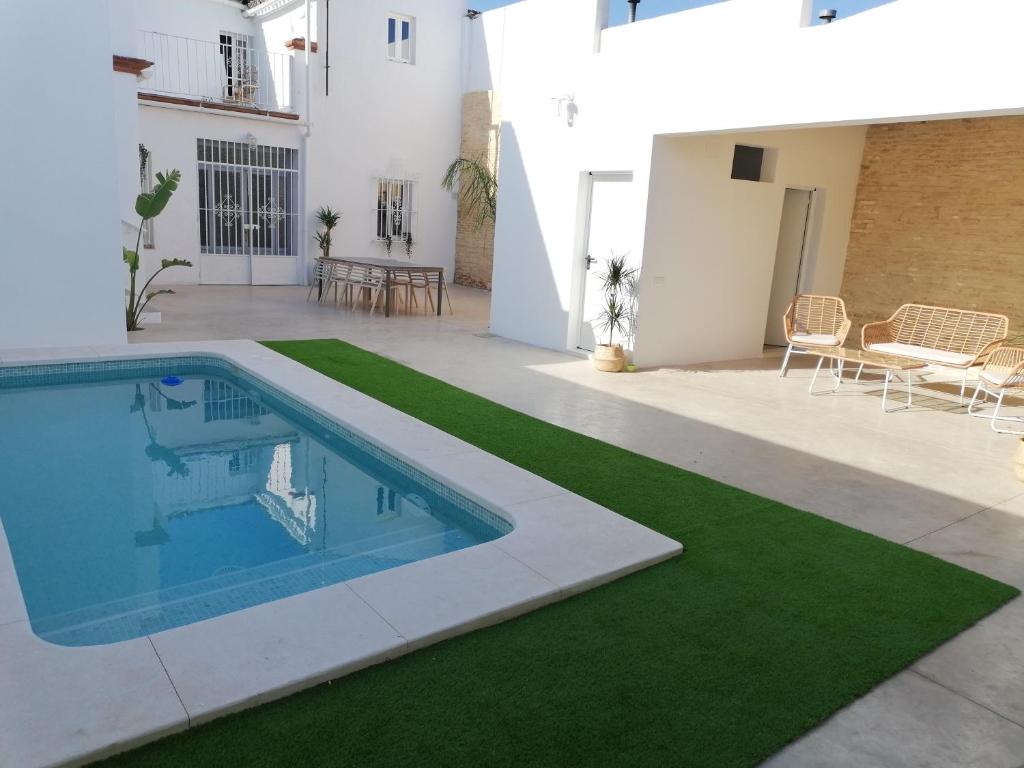 Villanueva del AriscalLa casa de los marqueses的一座带游泳池和绿色草坪的房屋