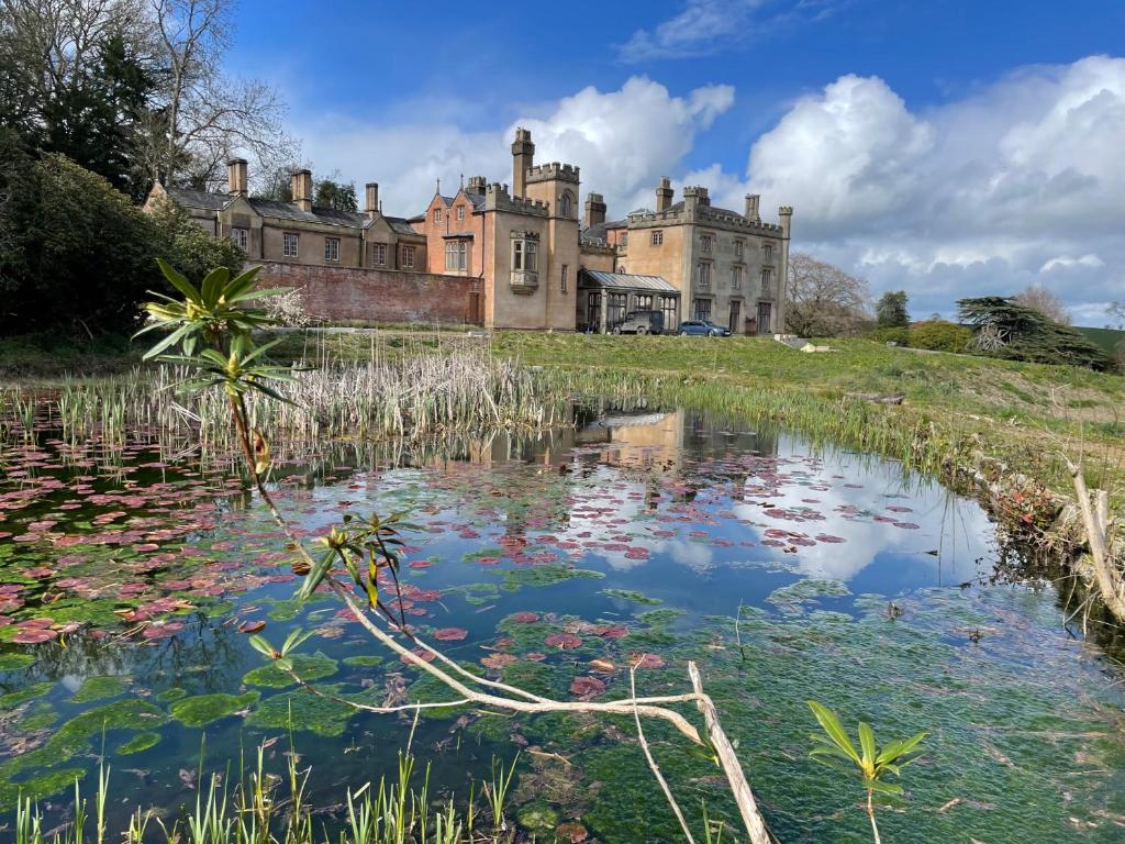 威尔斯浦Llanerchydol Hall Suites的一座城堡,前面有一个池塘