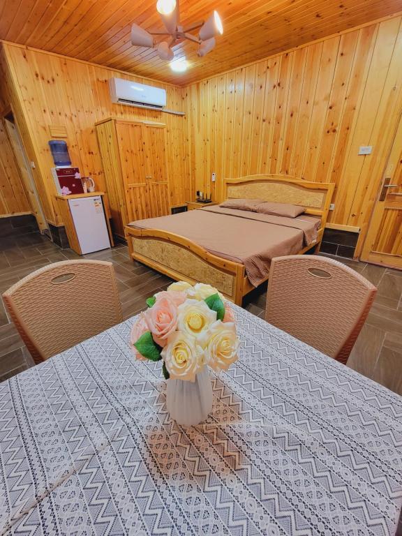 杰拉什atoom lodge的一间卧室配有一张床和一张鲜花桌子