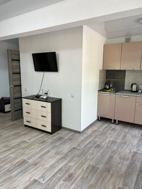 巴尔喀什Однокомнатная квартира в центре города的一间空房间,设有厨房和墙上的电视
