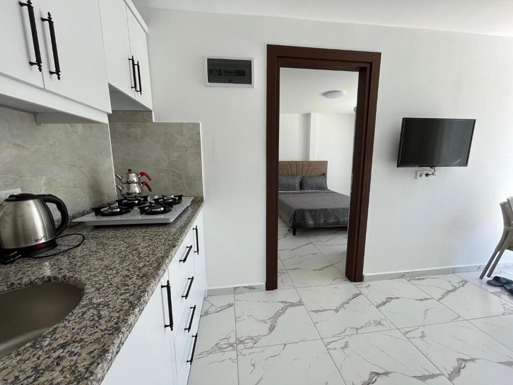 锡德Oğuz Apart的一间厨房,配有白色的橱柜和室内一台电视机