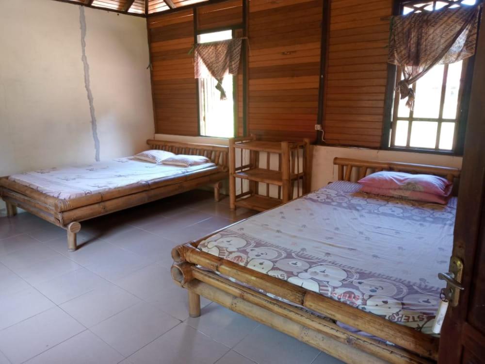 美娜多Lorenso Cottage的配有木墙和窗户的客房内的两张床