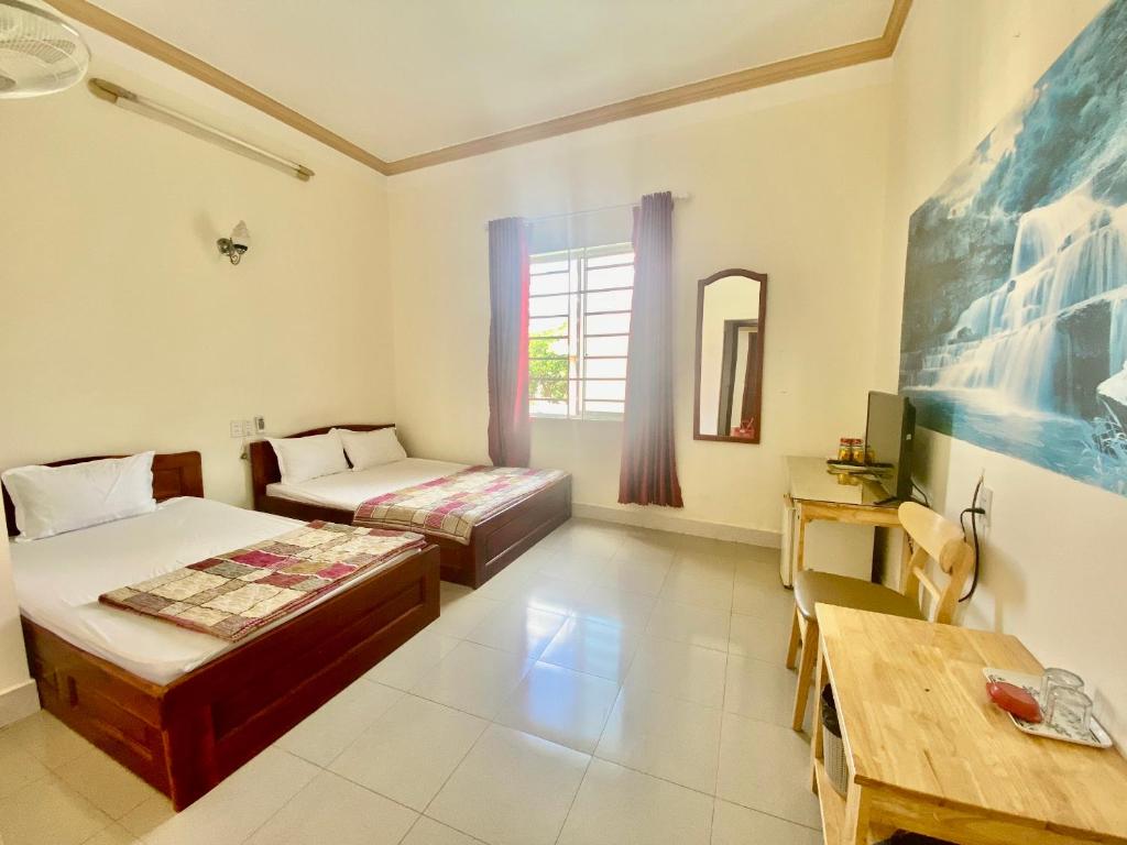 邦美蜀Khách sạn Ban Mê Xanh (Ban Me Xanh Hotel)的客房设有两张床、一张桌子和一张桌子。