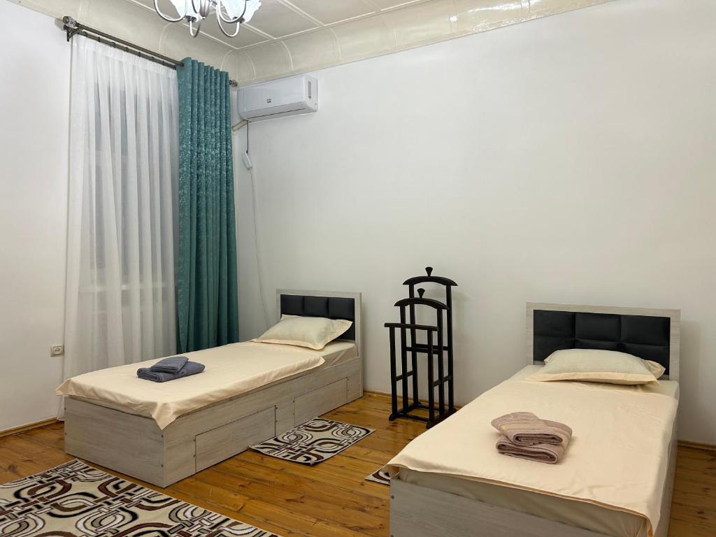 塔什干Humo Family Home的配有白色墙壁和木地板的客房内的两张床