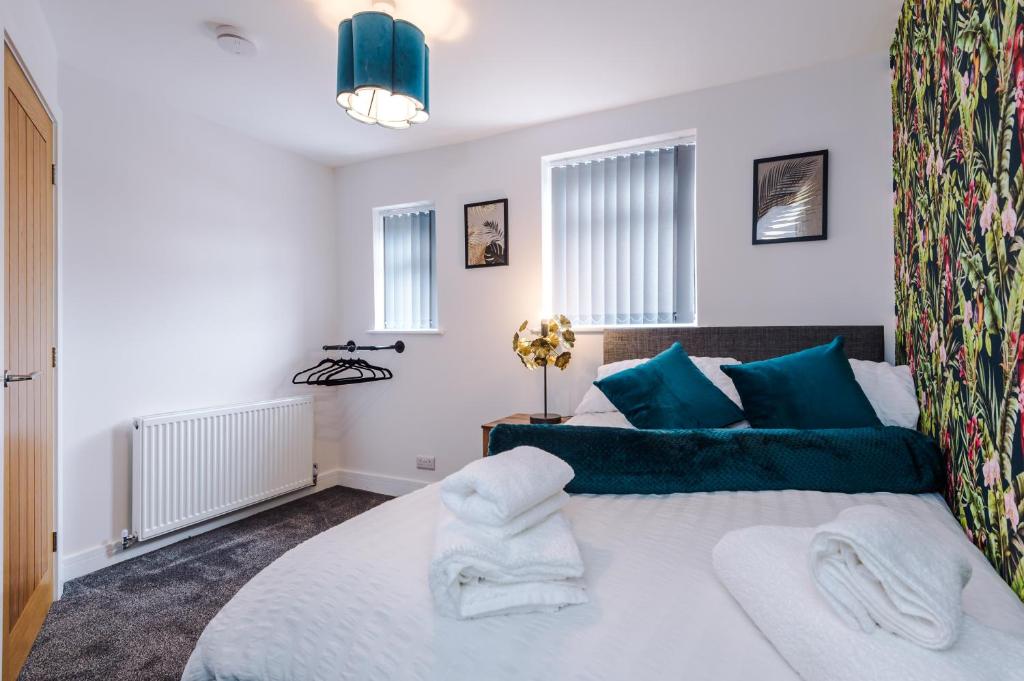 埃杰顿4 bed property, Bolton , Manchester的卧室配有带蓝色枕头的大型白色床
