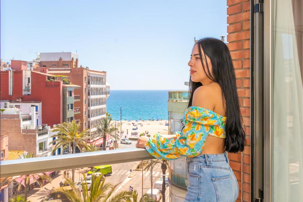 罗列特海岸Marina Beach Apartaments的站在一个眺望海洋的阳台上的女人