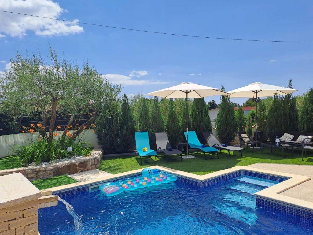 波雷奇Casa Vežnaveri的后院的游泳池配有椅子和遮阳伞
