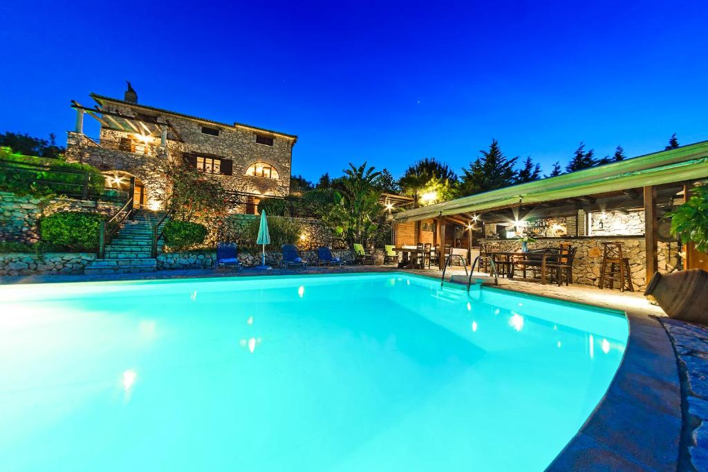 SkináriaVilla Poseidon Residence的夜间在房子前面的游泳池