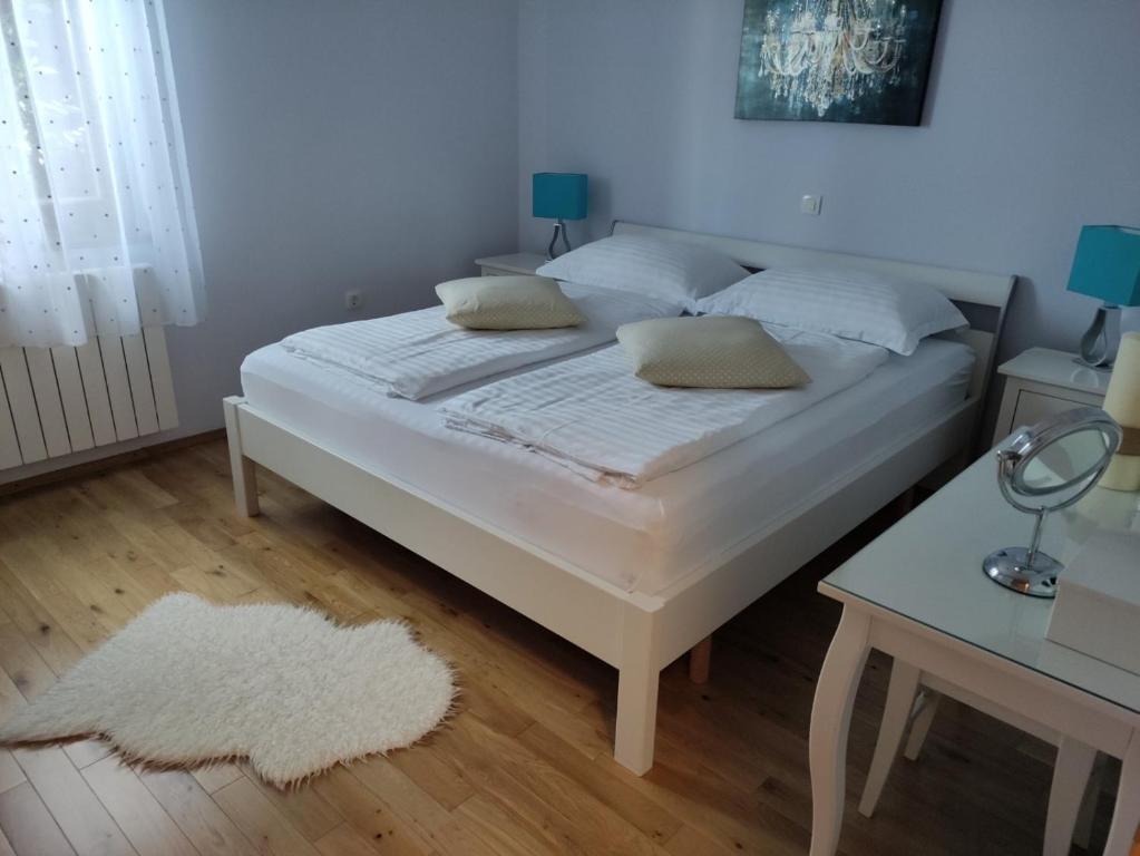 马图利Apartman Roža的卧室内的一张带白色床单和枕头的床