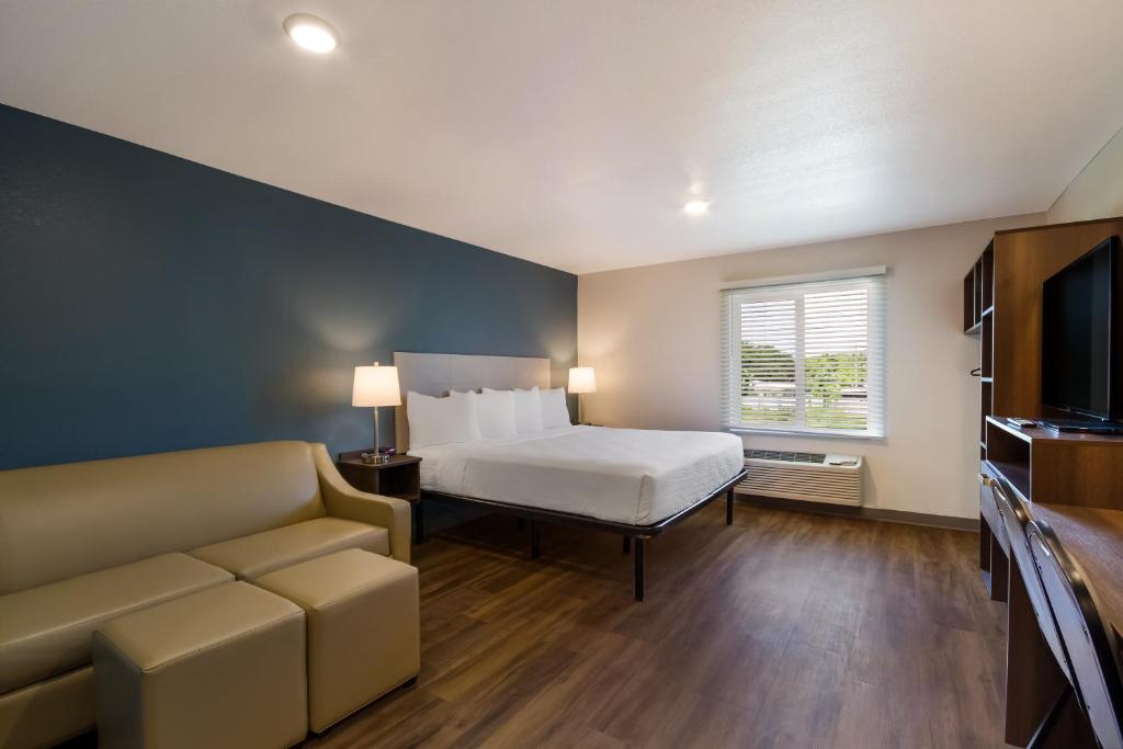 巴拿马城海滩WoodSpring Suites Panama City Beach的一间卧室配有一张床、一张沙发和一台电视