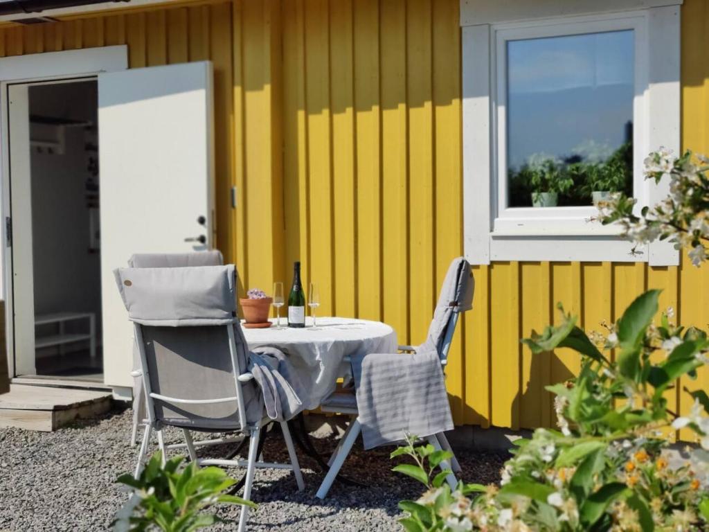 HolmsundGästhus nära naturen的黄色墙前的一张桌子和两把椅子