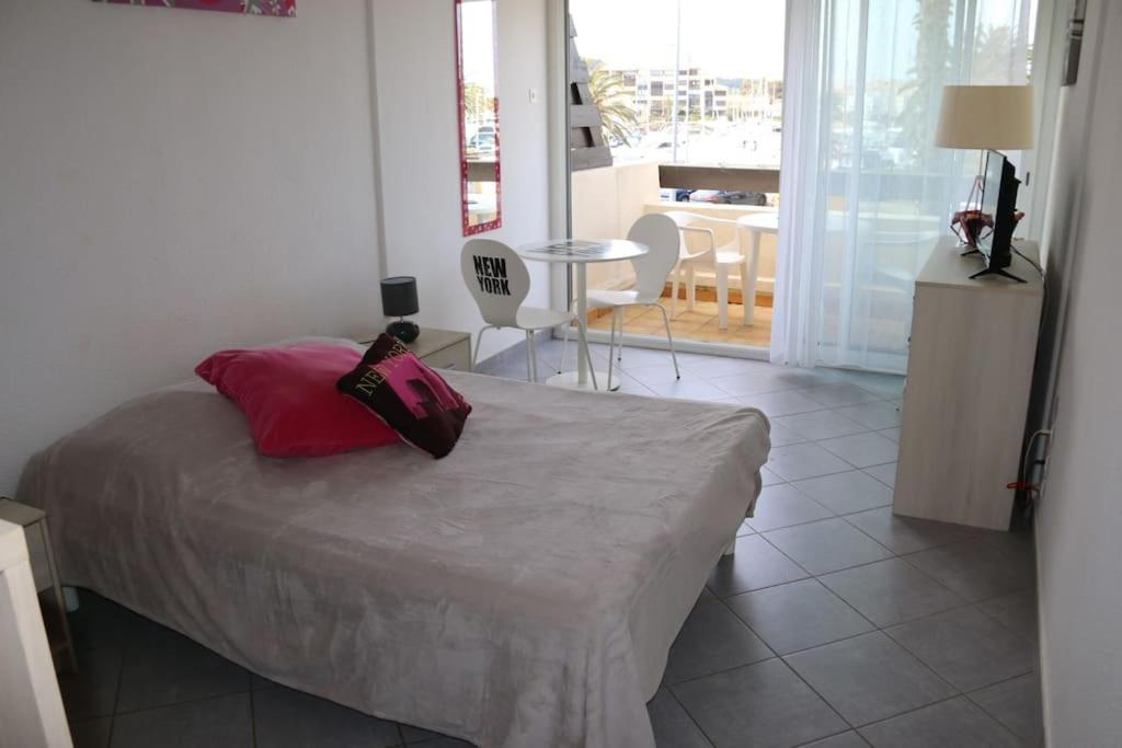 阿格德角Studio 721, Port Nature 7 au village naturiste的一间卧室配有一张带红色枕头和桌子的床