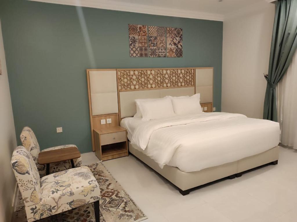 艾卜哈Kyan Park Abha Hotel的一间卧室配有一张大床和一把椅子
