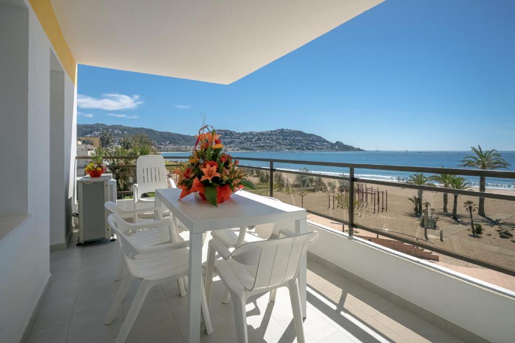 罗萨斯Inmosantos Oasis F5的阳台上配有白色的桌椅,享有海景