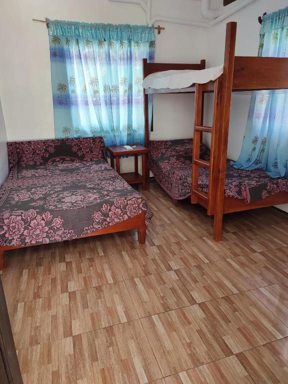 CapulCapul Beach Resort的客房设有两张双层床,铺有木地板。
