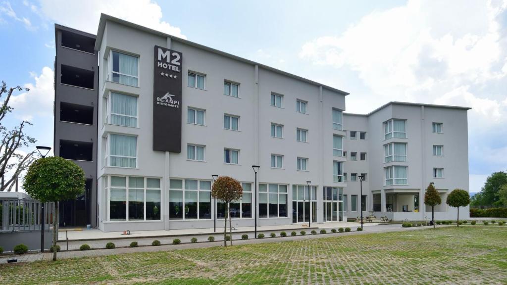 比森齐奥营M2 Hotel的一座白色的大建筑,上面有标志