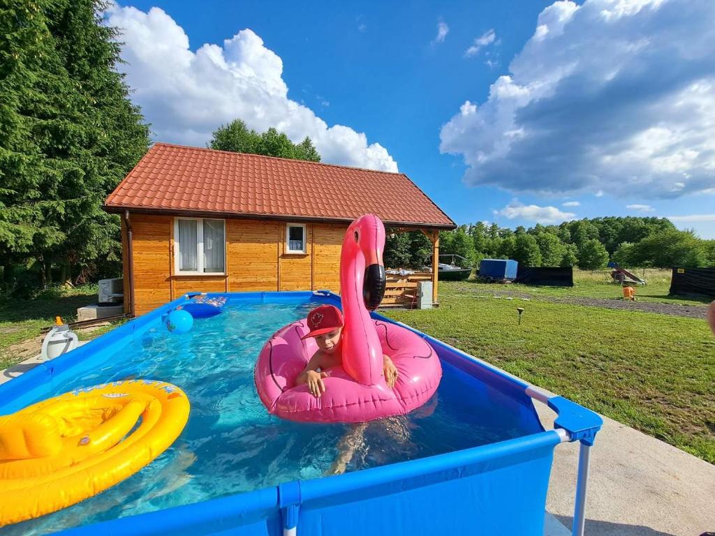 皮什Domki Snopki的游泳池里粉红色木筏上的孩子