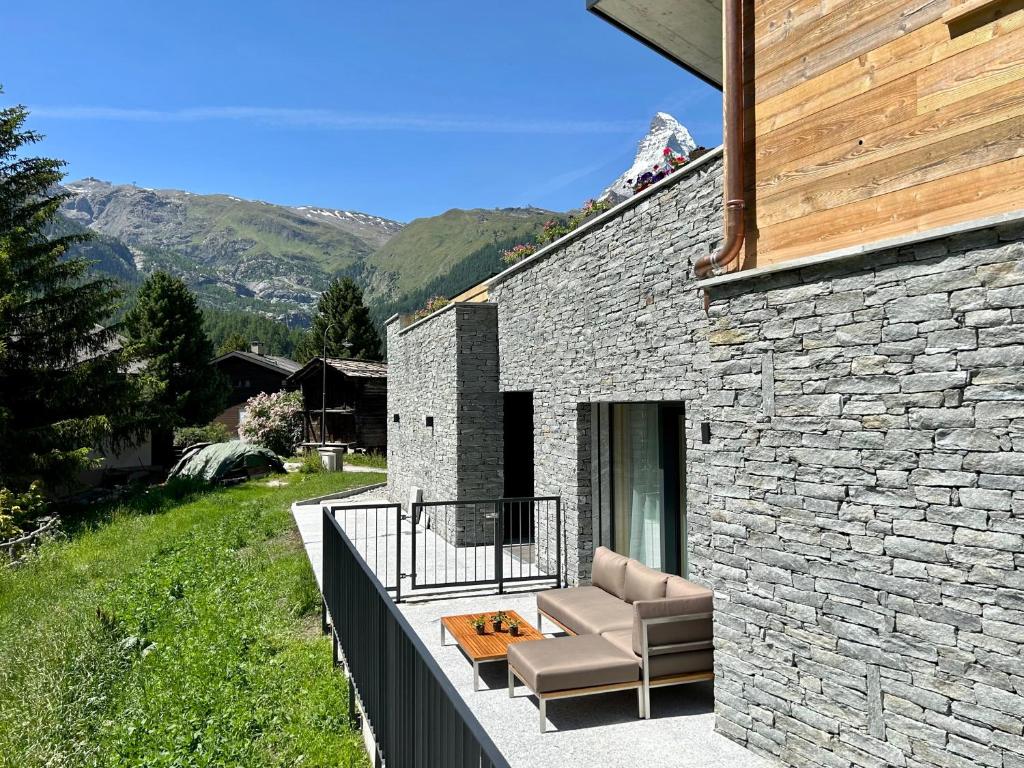 采尔马特Chalet Coral und Zermatter Stadel的石头房子,阳台上配有沙发