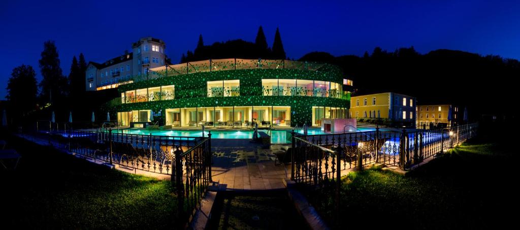 里姆斯克·托普利采Rimske Terme Resort - Hotel Rimski dvor的一座建筑,在晚上前方有一个游泳池