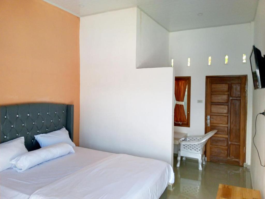 SinapuranRedDoorz @ Sihole Paradise Inn Parbaba的卧室配有1张床、1张桌子和1把椅子