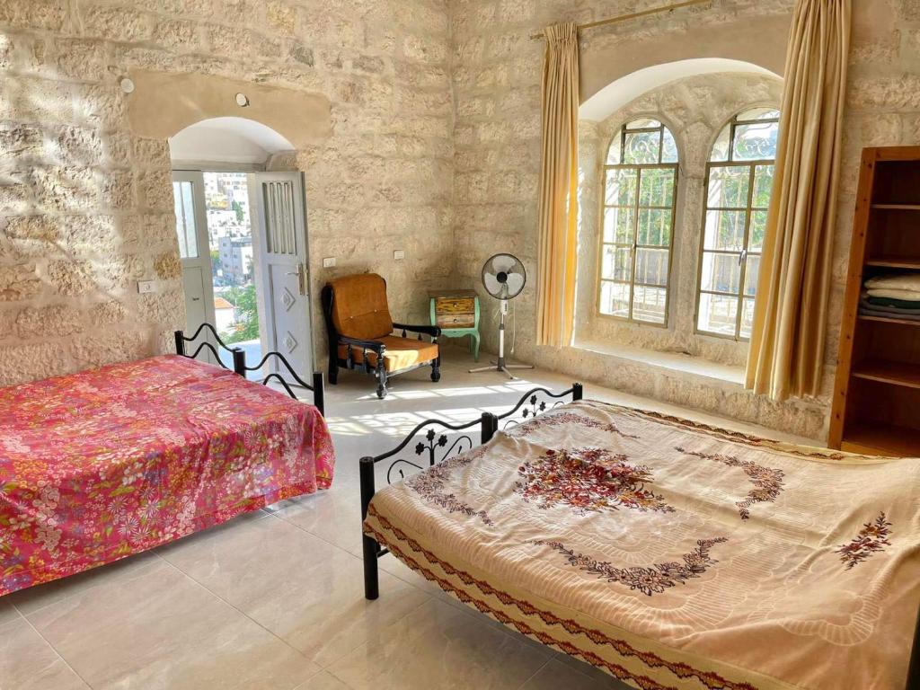 伯利恒Dar Ateeq's Arches/ Bethlehem Apartment的一间卧室配有一张床、一把椅子和窗户。