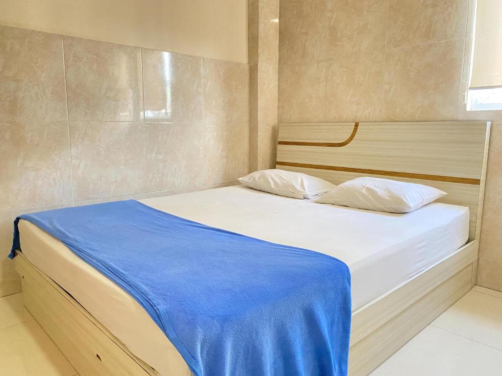 安汶Penginapan Star Ambon Mitra RedDoorz的一间卧室配有一张带蓝色毯子的床