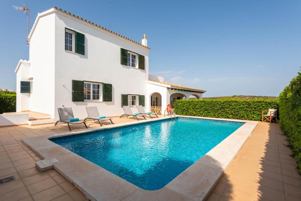 马翁Villa Cala Llonga的别墅前设有游泳池
