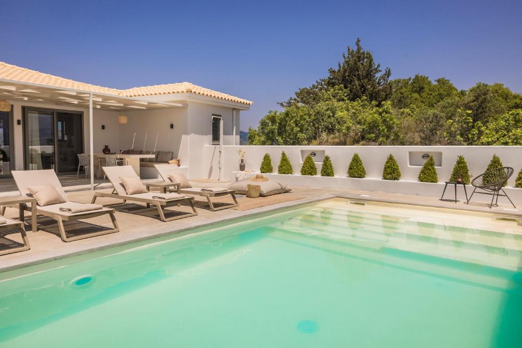 LépedhaVilla Mirto - Iris sunset villas的一个带椅子的游泳池以及一座房子