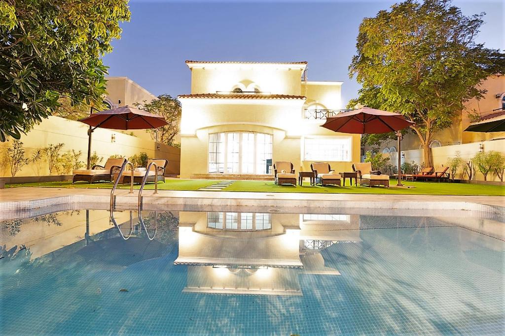 迪拜Dubai Marina Villa up 20 guest huge Private Pool的一座房子,设有一座带椅子和遮阳伞的游泳池