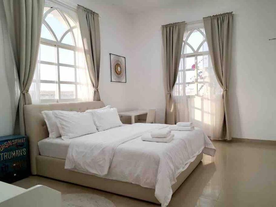 拉斯阿尔卡麦Villa 9 Palms Beach的一间卧室配有一张带白色床单的床和两个窗户。