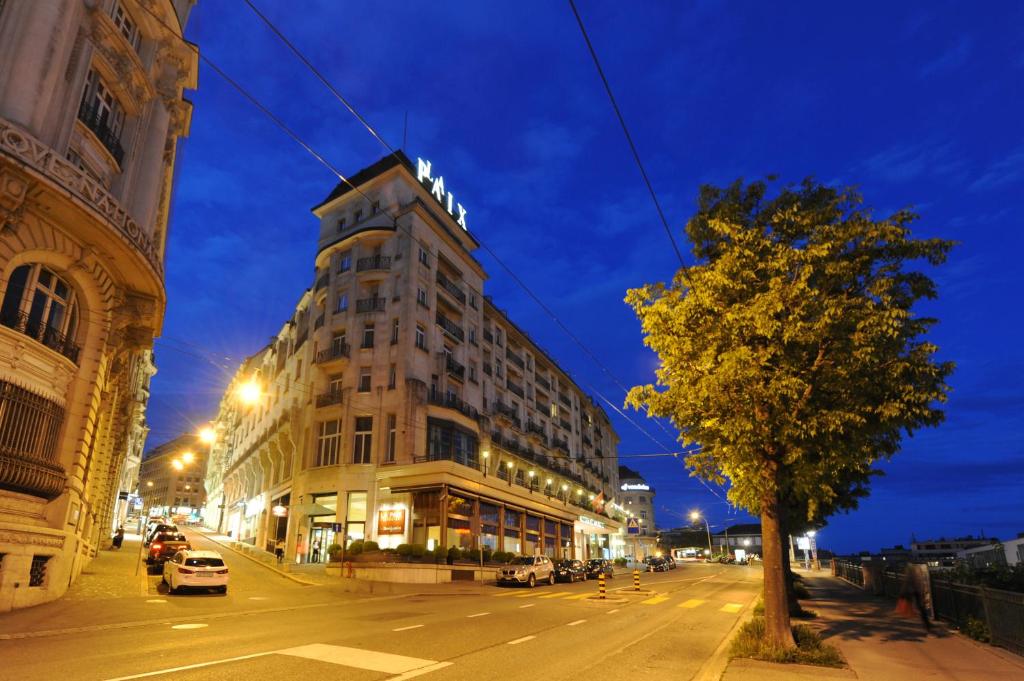 洛桑洛桑和平酒店的夜幕降临的城市街道上一座高楼