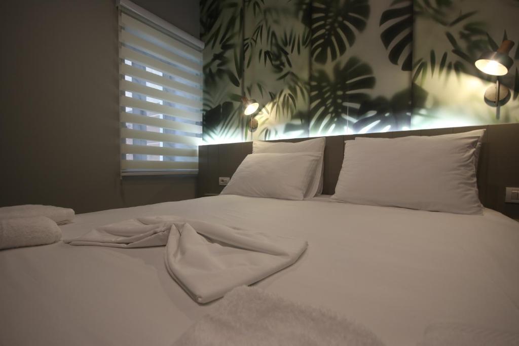 希马拉Alyvia Rooms的卧室内的一张带白色床单和枕头的床