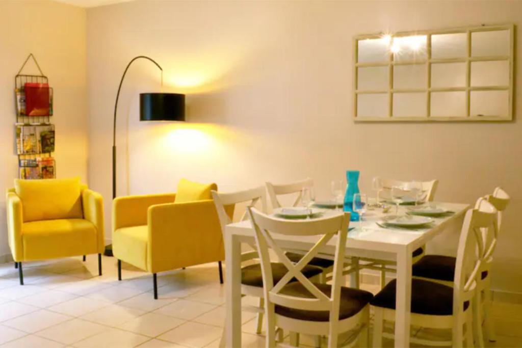 普瓦捷Maison St Eloi by iZiLi *Futuroscope*Jardin*的一间设有白色桌子和黄色椅子的用餐室