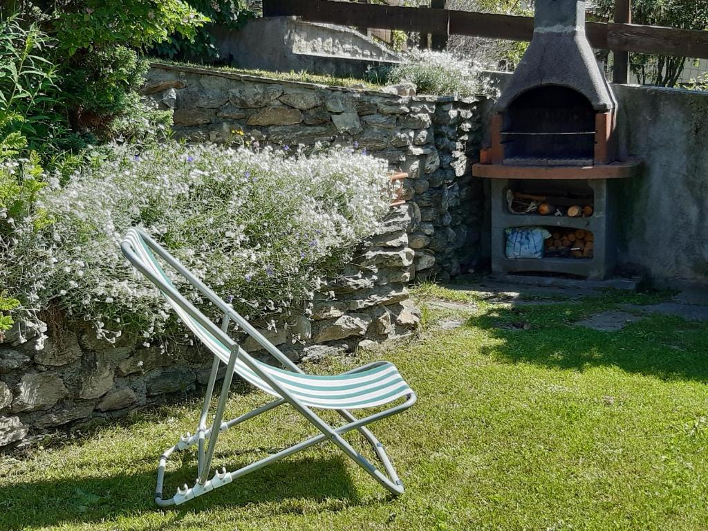萨奥兹-杜尔克斯Sauze d'Oulx with garden, ciabot la garitüla - wifi的坐在石炉旁的草地上的椅子