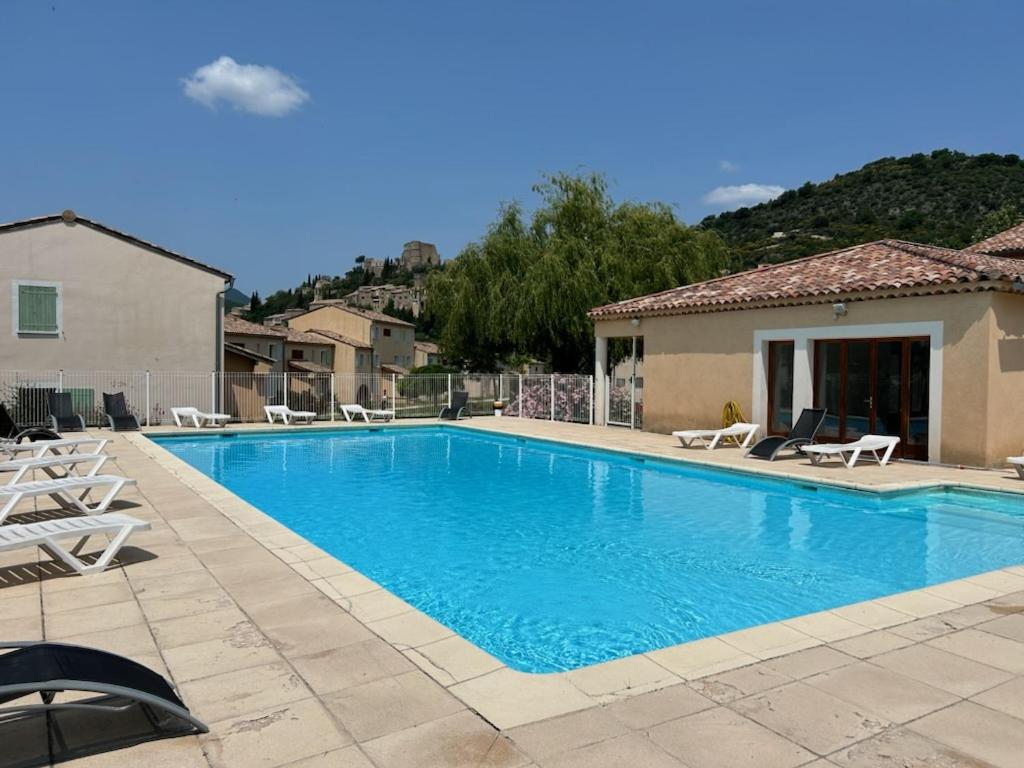 蒙布兰莱班Olydea Montbrun-les-Bains的一个带椅子的游泳池以及一座房子