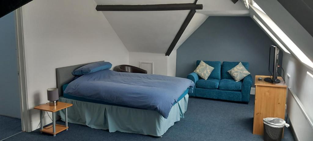 卡菲利Ty Castell Guest House的一间卧室配有一张床和一张蓝色的沙发