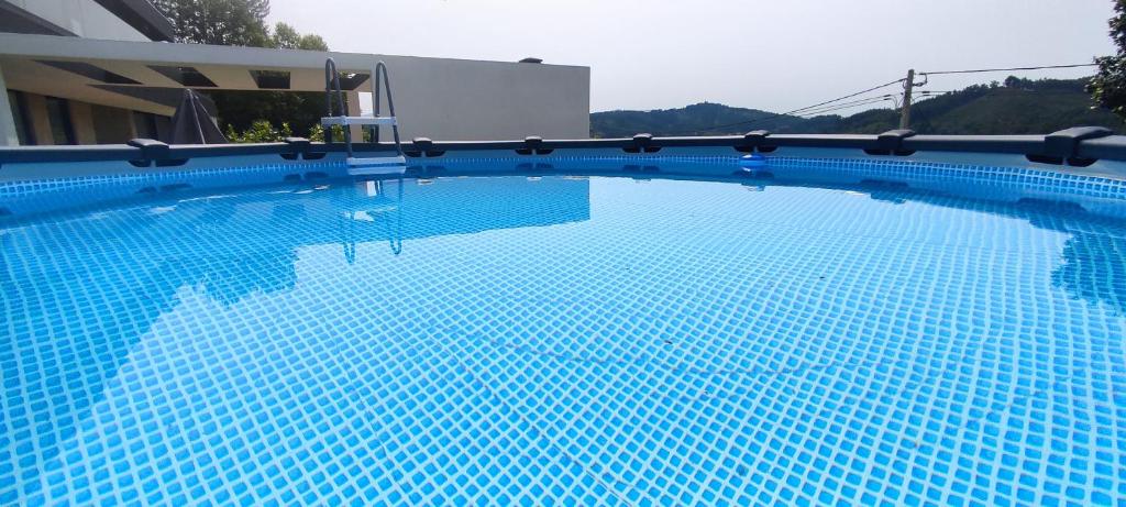 塞洛里库迪巴什图Casa de Silvares的大楼前的蓝色海水大型游泳池