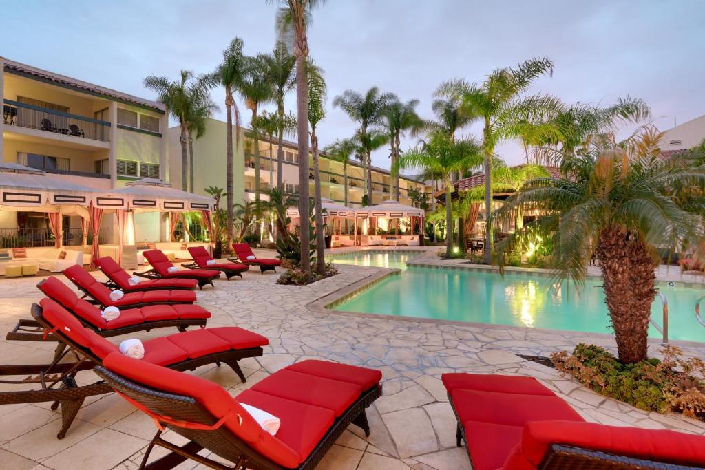 尔湾奥兰治县中庭酒店的一个带椅子的度假村和一个棕榈树游泳池