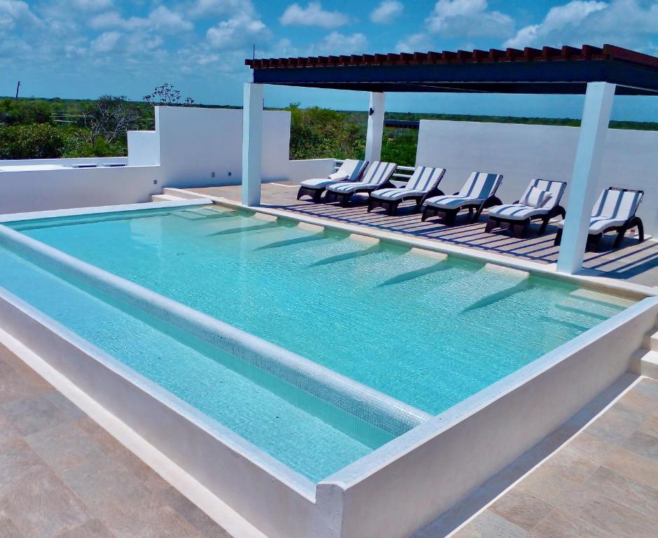 艾库玛尔Condominio en la Riviera Maya的一个带椅子和凉亭的大型游泳池