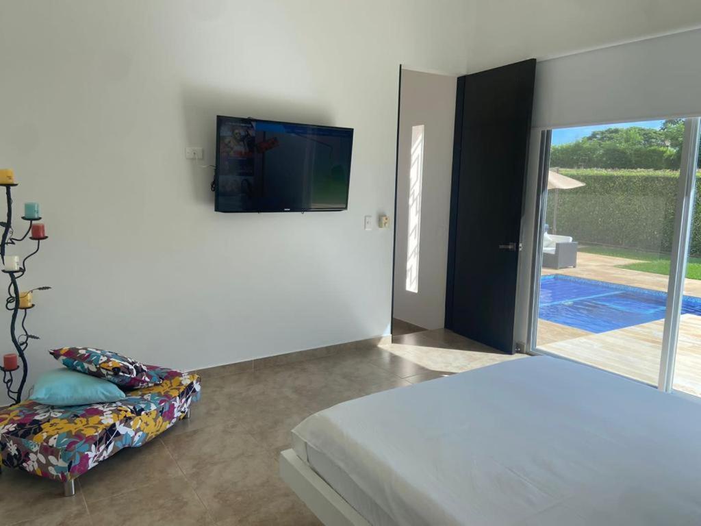 吉拉尔多特Girardot Casa estilo mediterraneo con piscina privada的一间卧室配有一张床,墙上配有电视