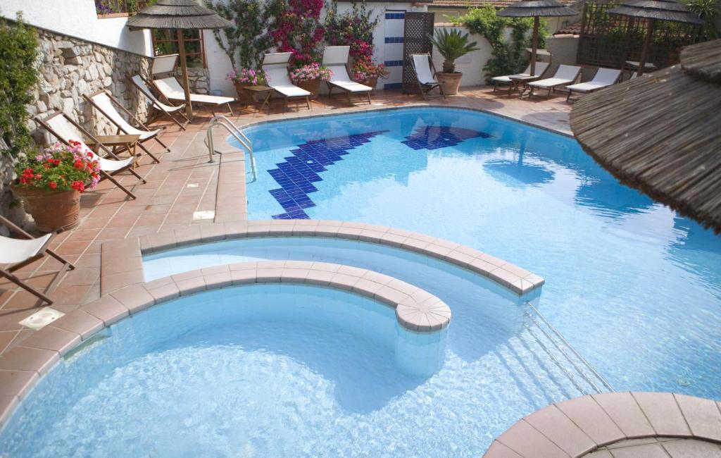 圣安德烈亚巴萨里尼酒店的度假酒店内带椅子和椅子的大型游泳池