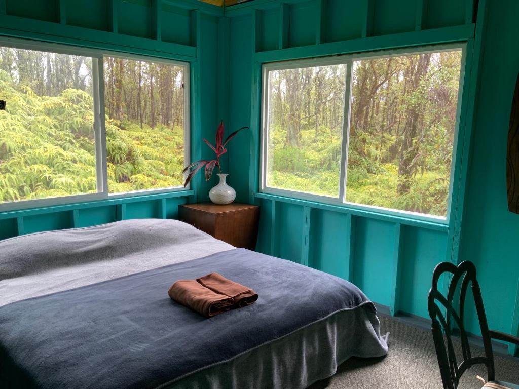 芒廷维尤Simple Rustic studio deluxe bed in tropical fruits garden的一间拥有蓝色墙壁的卧室和一张带两个窗户的床